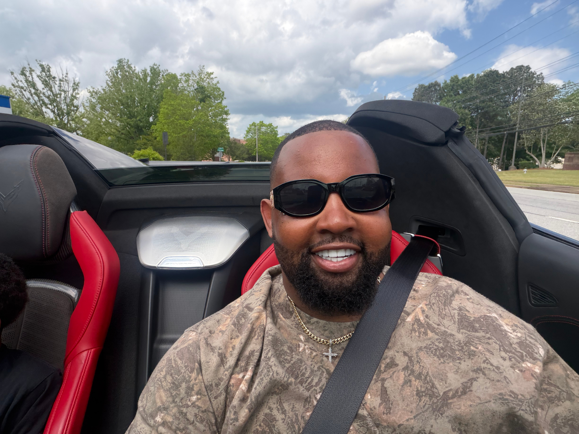 Bruce Webb smiling in his red-interior Corvette convertible